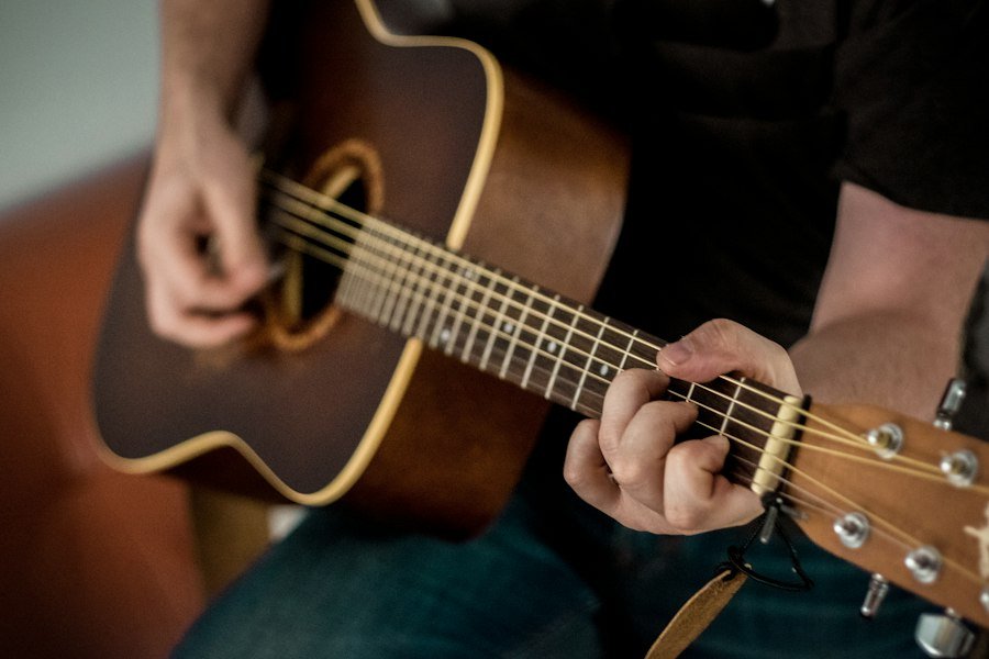 Hands playing a steel-string acoustic guitar